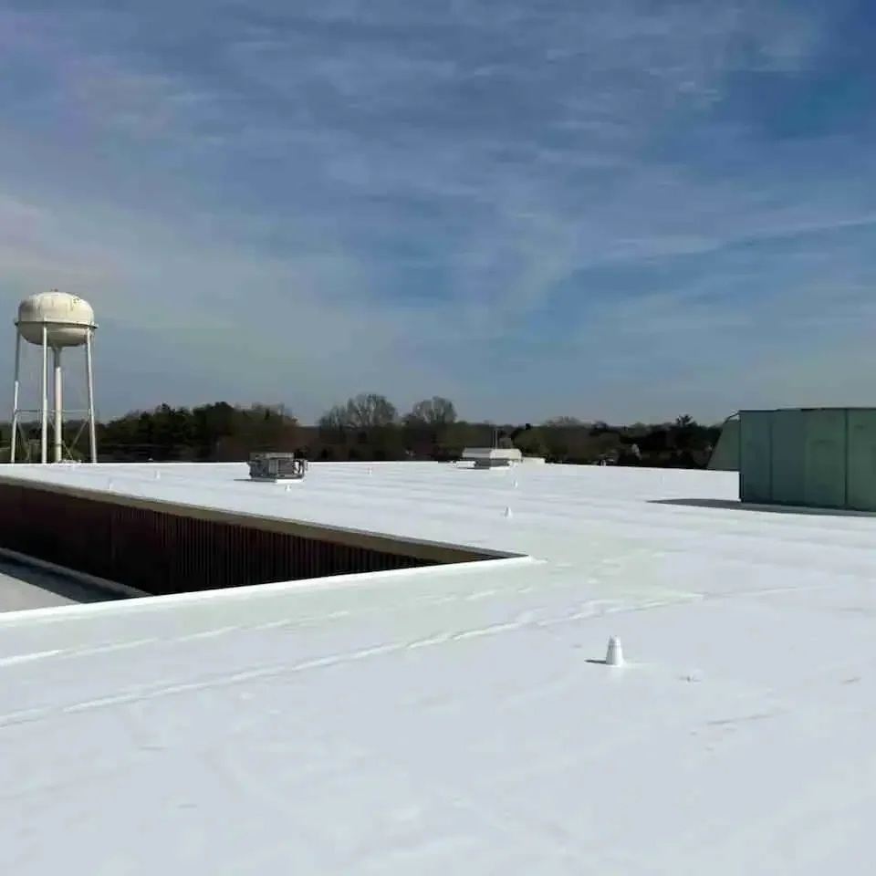 Roofing installation on commercial building with white reflective roof surface.