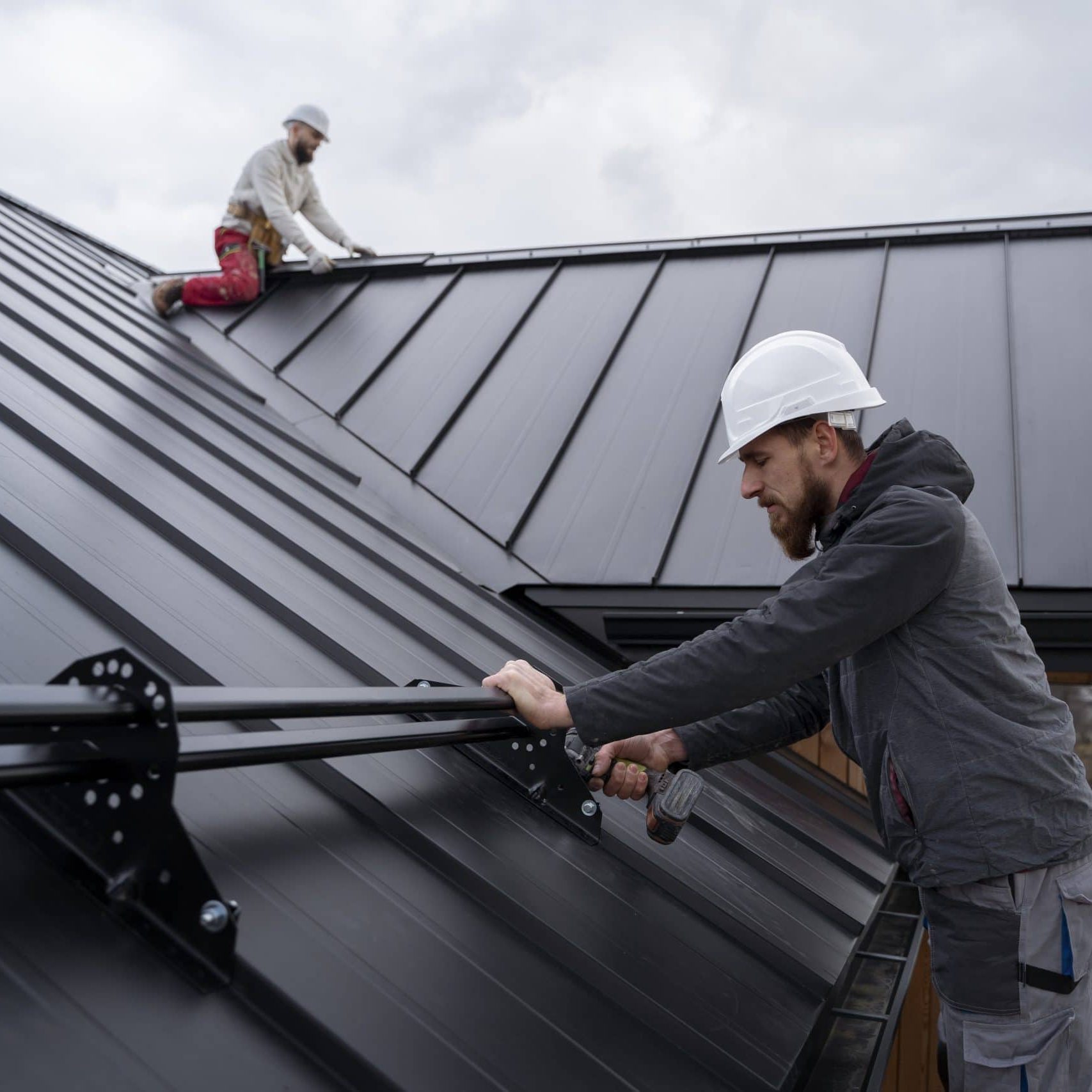 Metal roof installation by Davis Roofing Co Inc with workers securing panels on a residential buildi.