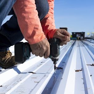 Roofing installation on metal roof panels with a cordless drill.